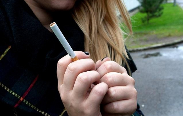 paauglė laiko cigaretę rankoje